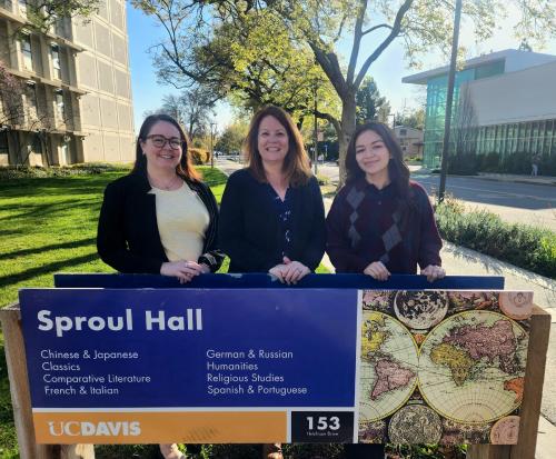 Three women standing behind a sign