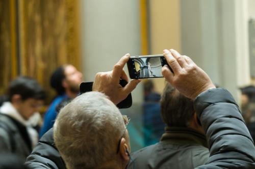 a man using his smartphone to take a picture of the statue of david