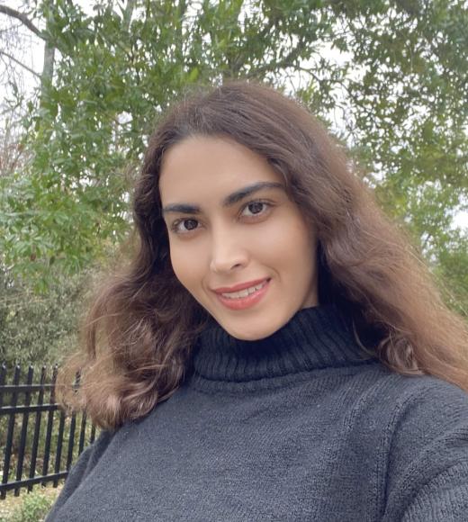 Outdoor head-and-shoulders photo of smiling woman with long brown hair in dark turtleneck