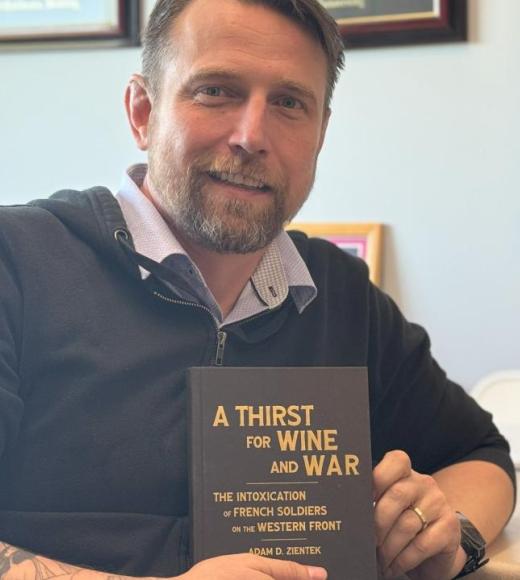 Man posing with the book he wrote