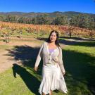 Ximena Landeros Bravo stands in front of a vineyard.
