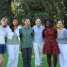 A photo of six students outdoors, standing in a line, smiling