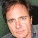 Man in gray shirt looking directly at the camera