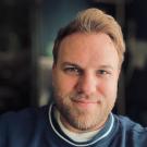 A photo of a man with a beard in a blue sweater