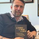 Man posing with the book he wrote